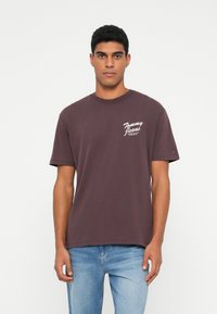 Bordo puuvillane T-särk ümmarguse kaelusega ja lühikeste varrukatega. Vasakul rinnal on valge "Tommy Jeans" logo. Puhtne disain.