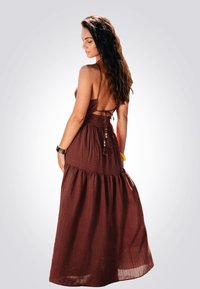 Bruine maxi-jurk met een aansluitend lijfje en een gelaagde rok. Heeft een strikdetail op de rug en een textuurstof. Versierd met decoratieve kralen.