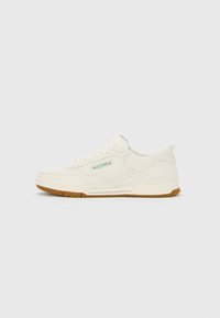 Off-white Skechers sneaker with gum sole, side perforations, lace-up design, and small green and red Skechers logo on the side panel.