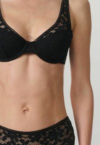 Soutien-gorge en dentelle noire avec un motif floral, soutien-gorge à armatures et bretelles ajustables. Texture lisse avec des bords festonnés et un design en V.