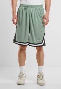 Lys grønne træningsshorts med sort og hvid accent, der har en elastisk talje og en knælang pasform. Glat, åndbart stof.