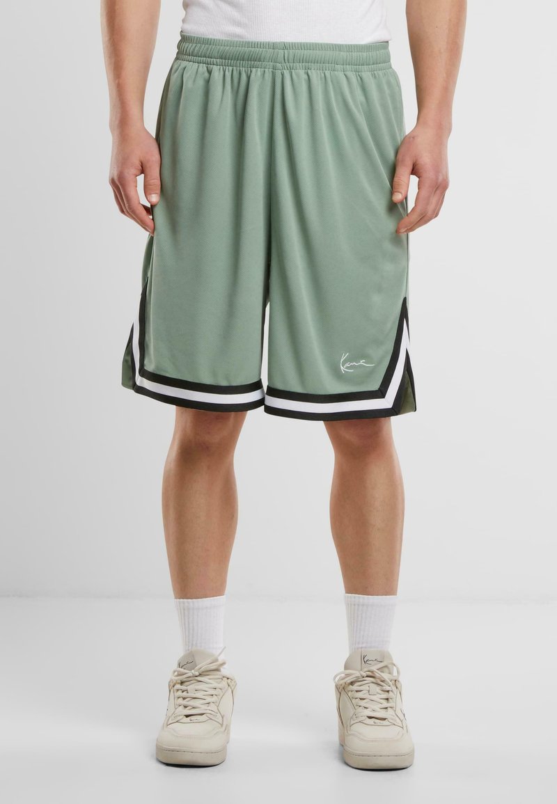Lys grønne træningsshorts med sort og hvid accent, der har en elastisk talje og en knælang pasform. Glat, åndbart stof.