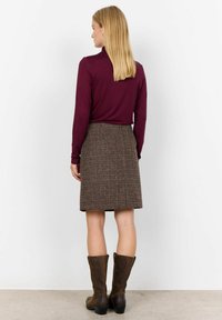 Langærmet bordeaux top, brun tweed nederdel, knæhøje brune læderstøvler. Har en skræddersyet pasform og subtil vævet tekstur.