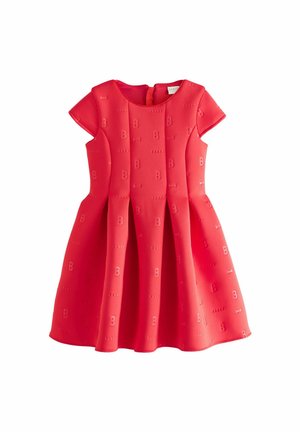 Robe rouge à manches courtes, en tissu texturé avec un motif en relief de nœuds et de lettres. Jupe plissée ajoutant du volume. Fermeture au dos.