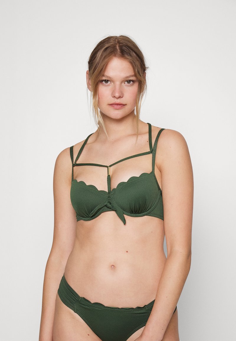 Conjunto de biquíni verde com um tecido texturizado, top estilo balconete com bordas onduladas, aros e múltiplas tiras finas com um detalhe central.
