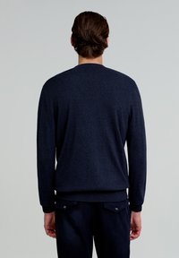 Mørkeblå sweater med rund hals, lange ærmer og ribbede manchetter og kant. Blød tekstur med ensfarvet mønster. Ingen synlige logoer eller detaljer.