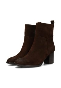 Botines de ante marrón con punta redondeada, un tacón bloque de altura media y una cremallera lateral para facilitar su uso. Diseño minimalista, textura suave.
