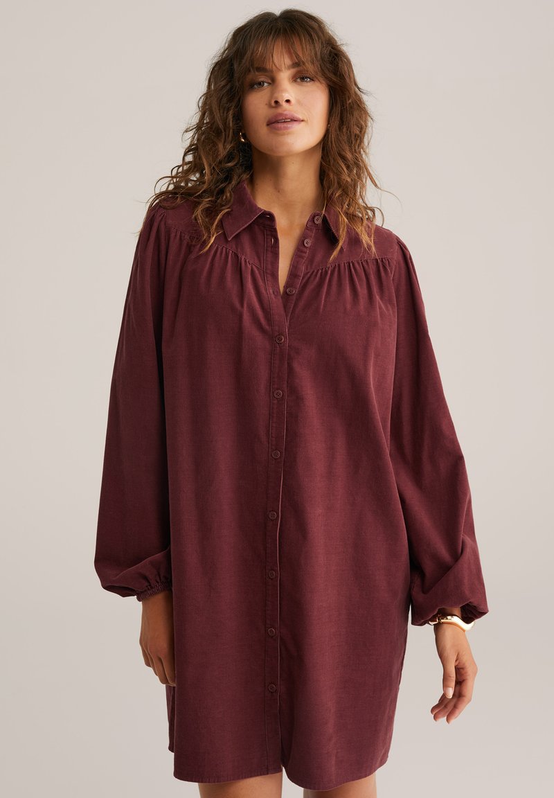 Burgundi värvi särgikleit nööpidega ees, lahtine lõige, kokku pandud õlavarre detail ja pikad varrukad elastsete mansettidega. Sile kangastekstuuri.