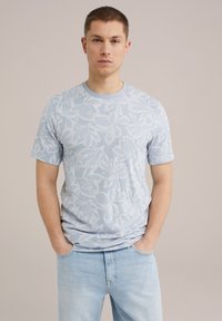 Világoskék, rövid ujjú póló, textúrált virágmintával és kerek nyakkivágással, világoskék farmernadrággal párosítva.