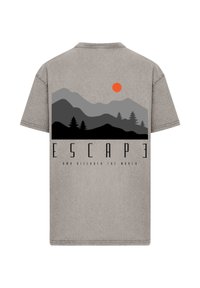 Grey cotton t-shirt featuring mountain and forest graphic in dark tones, with a bright orange sun and bold text "ESCAPE AND DISCOVER THE WORLD."