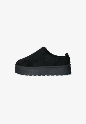 Scarpe slip-on nere in suede con superficie texture, punta arrotondata e suola in gomma spessa con grip. Dettagli di cucitura in evidenza.