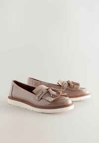 Vaaleanbeige patenttinanahkaiset loaferit, joissa on tupsut, kontrastoiva valkoinen kumipohja, koristeelliset tikkaus yksityiskohdat ja metalliset varusteet.
