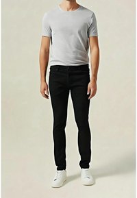 Gray cotton t-shirt, crew neck, paired with black slim-fit jeans. White sneakers complete the outfit. Plain design, no patterns or accents.