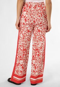 Szerokie spodnie w czerwono-białym wzorze z elastycznym paskiem w talii, z pionowymi paskami bocznymi i gładką teksturą materiału.