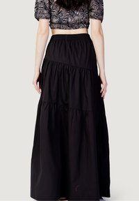 Schwarzer, gestufter Maxikleid aus leichtem Stoff. Besitzt einen elastischen Bund und subtile Nahtdetails. Glatte Textur.