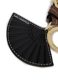 Must mustra raha võtmehoidja fänni disainiga, millel on kuldne riistvara ja valge õmblus. Tootja "KARL LAGERFELD" on väljendatud reljeefse kui kaubamärgi ettenägemiseks.