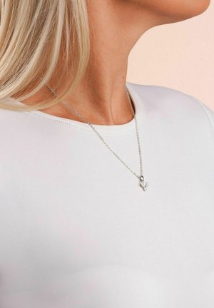 Silberne Kettenhalskette mit drei kleinen weißen Perlen, getragen von einer Frau mit blonden Haaren und einem weißen Rundhalsausschnitt-Oberteil.