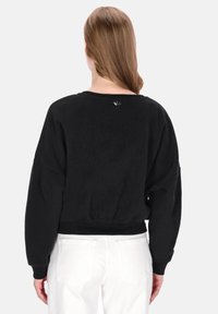 Černá mikina s volnějším střihem, žebrovanými manžetami a lemem a malým logem na zadním límci. Vyrobena z měkké, strukturované látky.
