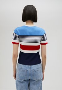 Kortärmad stickad tröja med blå, röd, vit och marinblå horisontella ränder samt rund halsringning. Tillverkad av mjukt, elastiskt material.