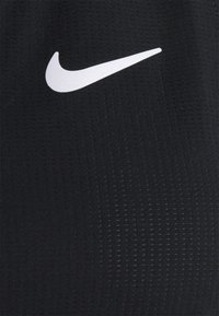 Tela atlética negra con un prominente logotipo de swoosh blanco de Nike, con una superficie texturizada y un patrón de ranuras verticales.