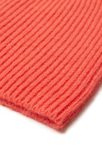 Tessuto a maglia rigata di un vivace colore corallo, caratterizzato da una texture morbida e una lieve peluria, con un focus sul motivo e sulla struttura del materiale.