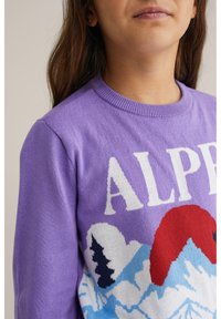 Lilla kudumitene särk, millel on mägede muster, punane päike, valged pilved ja sinised aktsendid. Ribitud kaelus. Tekst "ALP."