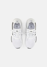 Zapatillas deportivas blancas con parte superior de malla texturizada, puntera redonda, cordones blancos planos y detalles grises en la suela y el talón.