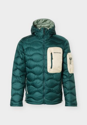 Veste matelassée verte à capuche avec poches zippées beiges sur la poitrine et les bras, fermeture éclair frontale, et logo "Peak Performance" sur la poche poitrine.