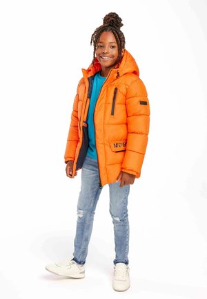 Orange puffer jacket with hood, zipper front, and black accents. Worn over a blue shirt, paired with distressed jeans and white sneakers.