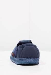 Marineblauwe slipper met een gemêleerd stoffen bovenwerk, voorzien van een denimaccent aan de achterkant en een gevoerde zool met een robuuste rand.