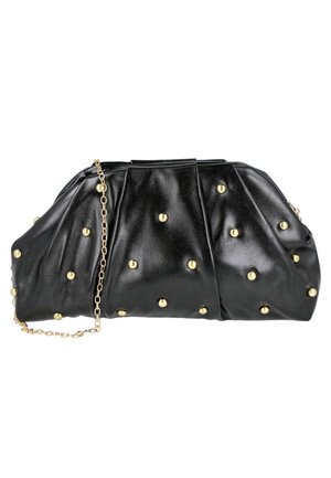 Bolso de mano de cuero negro con tachuelas redondas doradas y una correa delgada de cadena dorada sobre un fondo blanco.