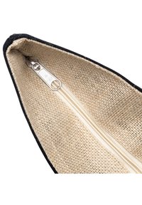 Gros plan d'une pochette en tissu beige tissé avec bordure noire et fermeture éclair argentée partiellement ouverte sur le dessus.
