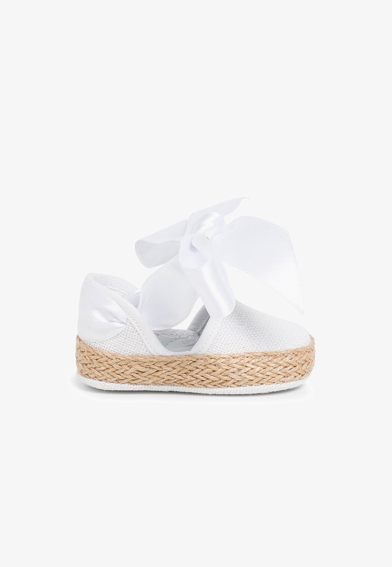 White espadrille shoe with a woven straw sole, mesh upper, and a large white bow tied at the ankle. Smooth texture throughout.