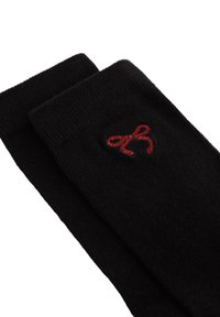 Črne nogavice iz mehkega materiala z rdečim vezenim lokom na eni strani. Oblikovanje vključuje rebrasto teksturo na vrhu.