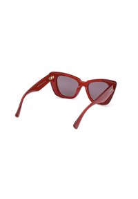 Gafas de sol rojas con forma de gato, lentes ahumados de color gris oscuro, montura de plástico brillante y varillas elegantes con detalles en dorado.