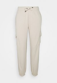 Beige sweatpants in soft fabric with an elastic waistband and adjustable drawstring. Features side cargo pockets and tapered ankles.