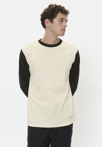 Crème en zwarte lange mouw t-shirt, met een ronde halslijn, contrasterende mouwen en een label met maatindicatie aan de zoom.