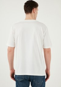 Hvid bomulds T-shirt med korte ærmer, rund halsudskæring og løs pasform. Glat overflade, standard kant, minimal pynt.