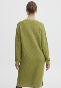 Stickad klänning i olivgrönt, med en strukturerad mönstring, långa ärmar, rund halsringning och sidofickor.