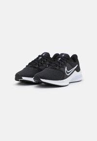 Zapatillas deportivas negras con parte superior de malla y acentos en blanco, con una suela exterior texturizada y cordones, diseñadas para la comodidad y el soporte.