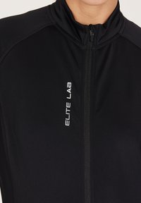Zwarte sportjack met hoge kraag, volledige rits en reflecterend "ELITE LAB" logo. Gemaakt van gladde, rekbare stof met een strakke pasvorm.