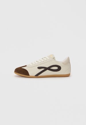 Sneakers con tomaia in tela color crema, puntale in suede marrone e un grande design astratto marrone scuro. Suola in gomma. Design casual e a profilo basso.