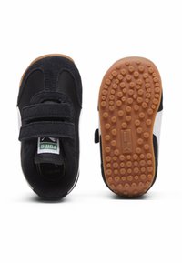 Schwarze und graue Kleinkinder-Sneaker mit Klettverschlüssen, ausgestattet mit einem weißen Seitenstreifen und einer strukturierten Gummisohle mit punktmusterartigem Grip.