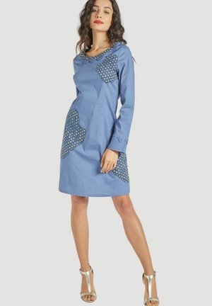 Vestido de algodón azul con mangas largas, escote redondo y bolsillos decorativos con estampado. Ligero brillo, largo hasta las rodillas y diseño ajustado.