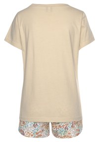 Beige katoenen t-shirt met een ronde hals en korte mouwen, gecombineerd met korte broek met een bloemenpatroon met oranje en blauwe accenten.