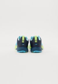 Baskets de sport avec un dessus bleu marine foncé, des accents bleu clair et vert fluo, une semelle texturée et un col rembourré pour le soutien.