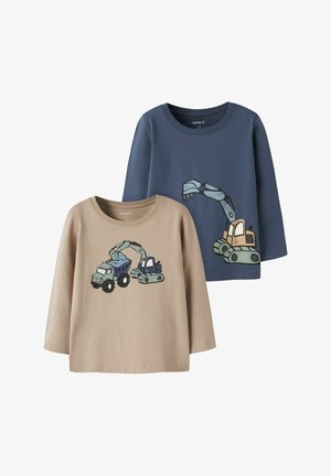 Deux chemises à manches longues pour enfants, une beige avec un motif de camion-benne et d'excavatrice, une bleue avec un grand motif de bras d'excavatrice.
