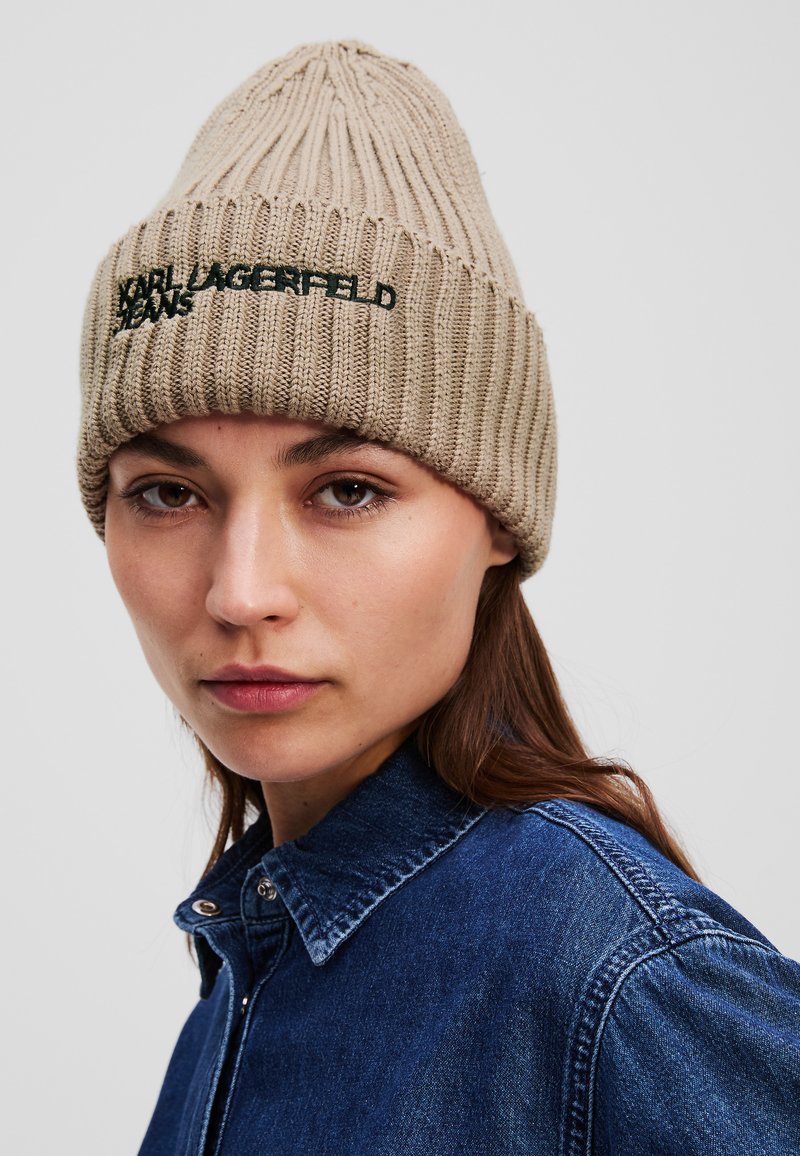 Beige bordázott kötött sapka hegyes tetejével. Elöl hímzett fekete "KARL LAGERFELD JEANS" felirat található.