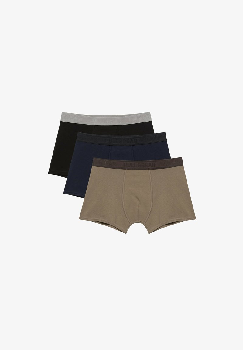 Trois paires de sous-vêtements pour hommes de style boxer en beige, bleu marine et noir, avec des ceintures élastiques assorties.