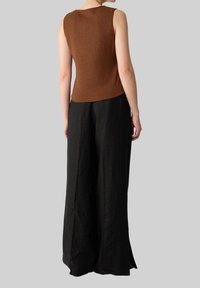 Brązowy teksturowany, bezrękawnik zestawiony z luźnymi, czarnymi spodniami o szerokich nogawkach. Stylizacja cechuje się eleganckim, minimalistycznym designem.